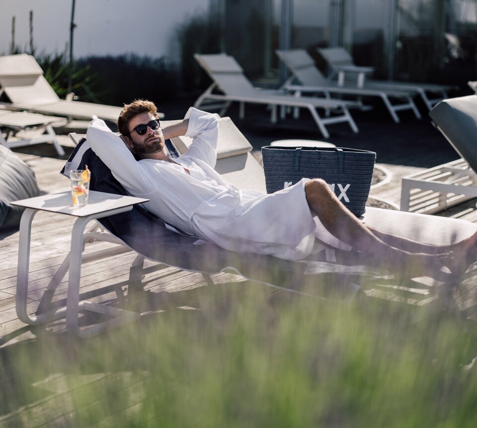 Mann mit Sonnenbrille entspannt auf einer Liege im Relax! Garten des Spa Resort Geinberg | © Spa Resort Geinberg / Chris Perkles