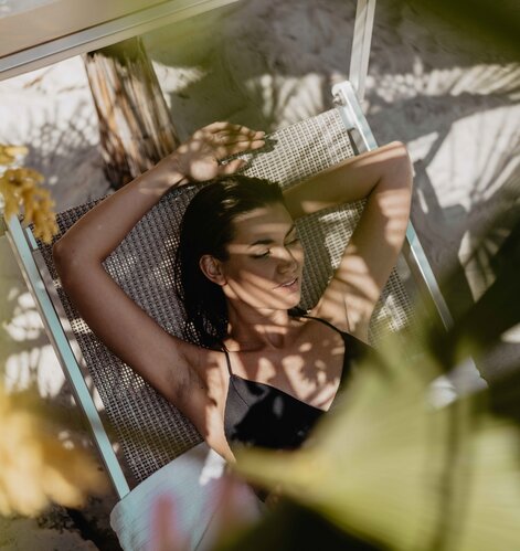 Braun gebrannte Frau genießt den Schatten der Palmen in der Karibik-Lagune im Spa Resort Geinberg | © Spa Resort Geinberg / Chris Perkles