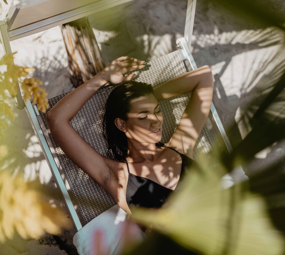 Braun gebrannte Frau genießt den Schatten der Palmen in der Karibik-Lagune im Spa Resort Geinberg | © Spa Resort Geinberg / Chris Perkles