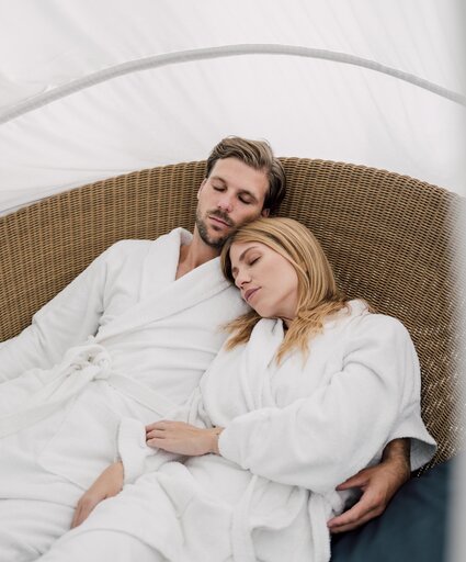 Paar im Bademantel entspannt mit geschlossenen Augen im Relaxation Korb des Spa Resort Geinberg | © Spa Resort Geinberg / Chris Perkles