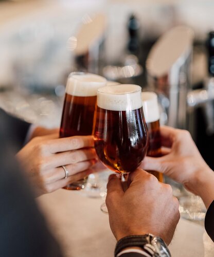 Eine kleine Personengruppe stößt mit Biergläsern an bei der Verkostung an der Hotelbar des 4*S Hotels | © Spa Resort Geinberg / Chris Perkles