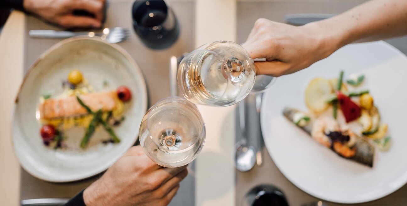 Detailaufnahme von zwei Weingläsern und dem exquisiten 5-Gang-Dinner im Hotelrestaurant des Spa Resort Geinberg | © Spa Resort Geinberg / Chris Perkles