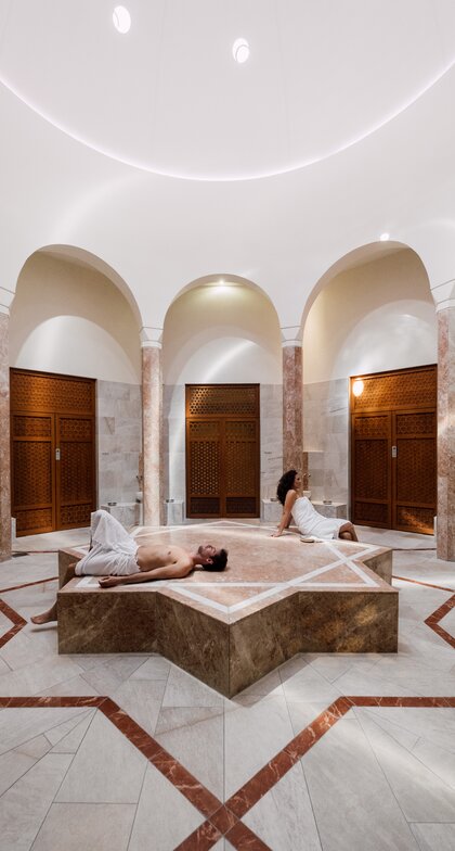 Paar genießt die Wärme des beheizten Nabelsteins in der Oriental World | © Spa Resort Geinberg / Chris Perkles