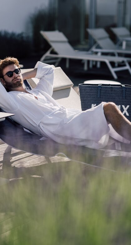 Mann mit Sonnenbrille entspannt auf einer Liege im Relax! Garten des Spa Resort Geinberg | © Spa Resort Geinberg / Chris Perkles