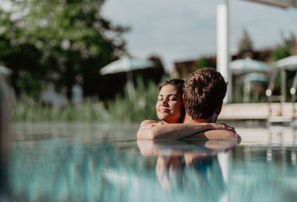 Paar genießt die Sonnenstrahlen im Pool der Karibischen Saunawelt im Spa Resort Geinberg | © Spa Resort Geinberg / Chris Perkles