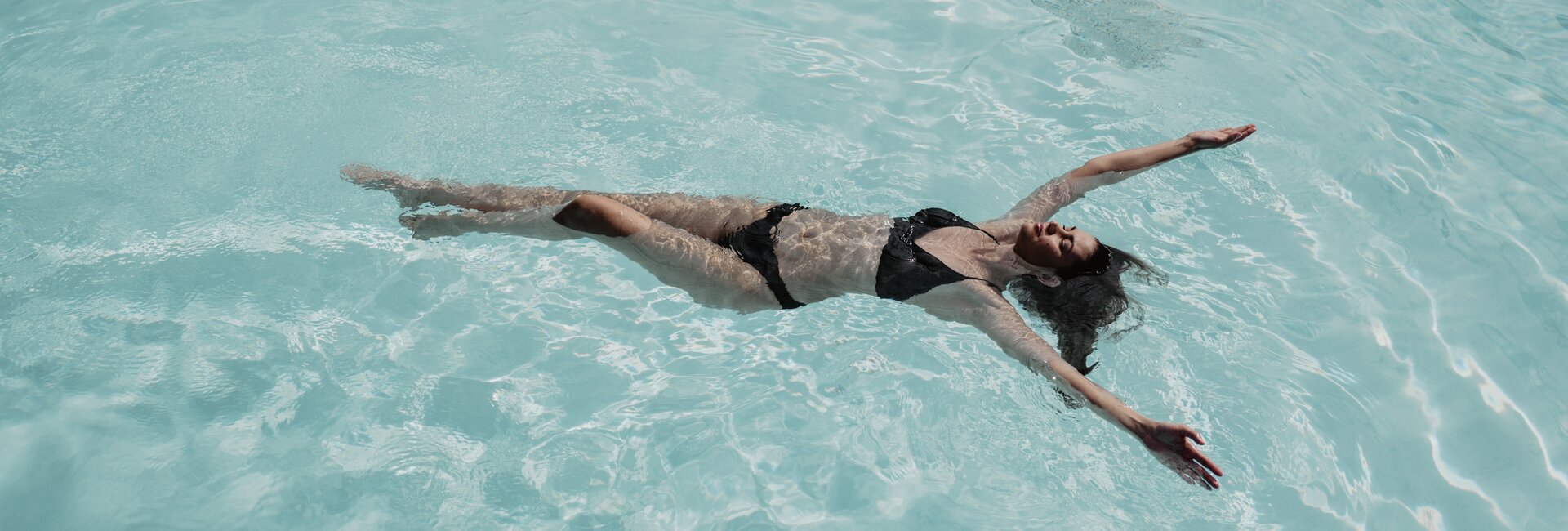 Dunkelhaarige Frau schwebt im Wasser der Therme im Spa Resort Geinberg | © Spa Resort Geinberg / Chris Perkles