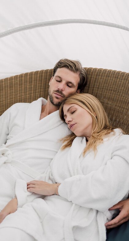 Paar im Bademantel entspannt mit geschlossenen Augen im Relaxation Korb des Spa Resort Geinberg | © Spa Resort Geinberg / Chris Perkles