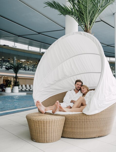 Paar im Bademantel entspannt gemütlich im Relaxation Korb der Thermen-Innenhalle im Spa Resort Geinberg | © Spa Resort Geinberg / Chris Perkles