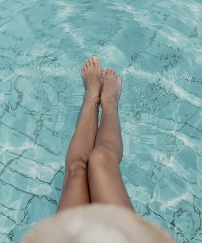 Nahaufnahme von Damen-Beinen im Wasser des Thermal-Beckens outdoor im Spa Resort Geinberg | © Spa Resort Geinberg / Chris Perkles