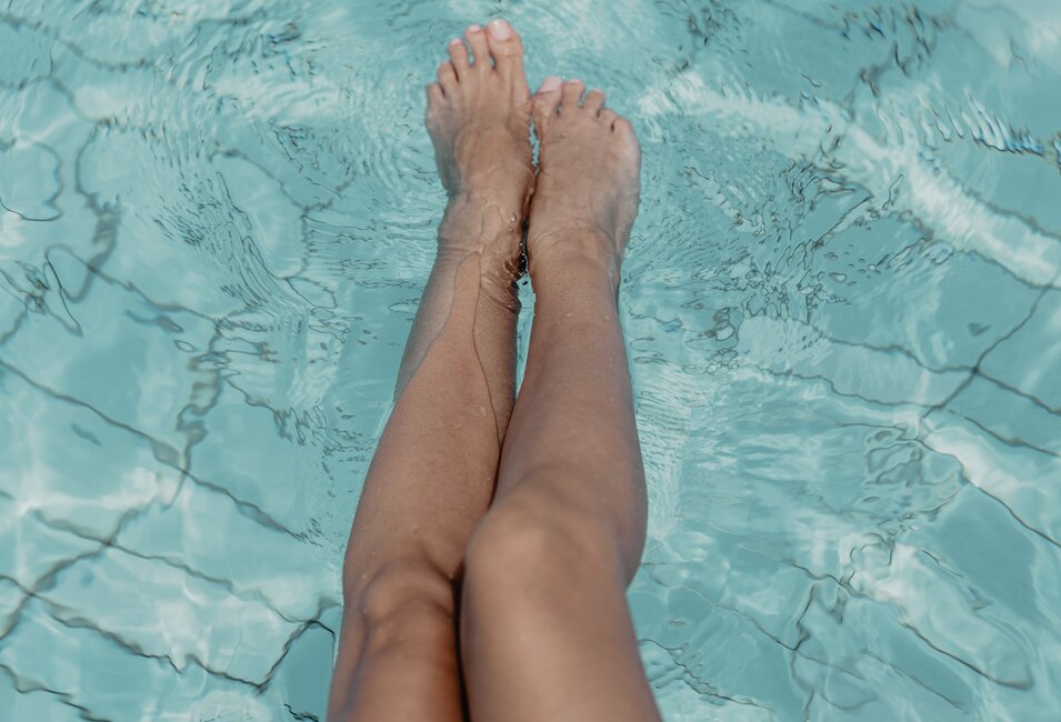 Nahaufnahme von Damen-Beinen im Wasser des Thermal-Beckens outdoor im Spa Resort Geinberg | © Spa Resort Geinberg / Chris Perkles