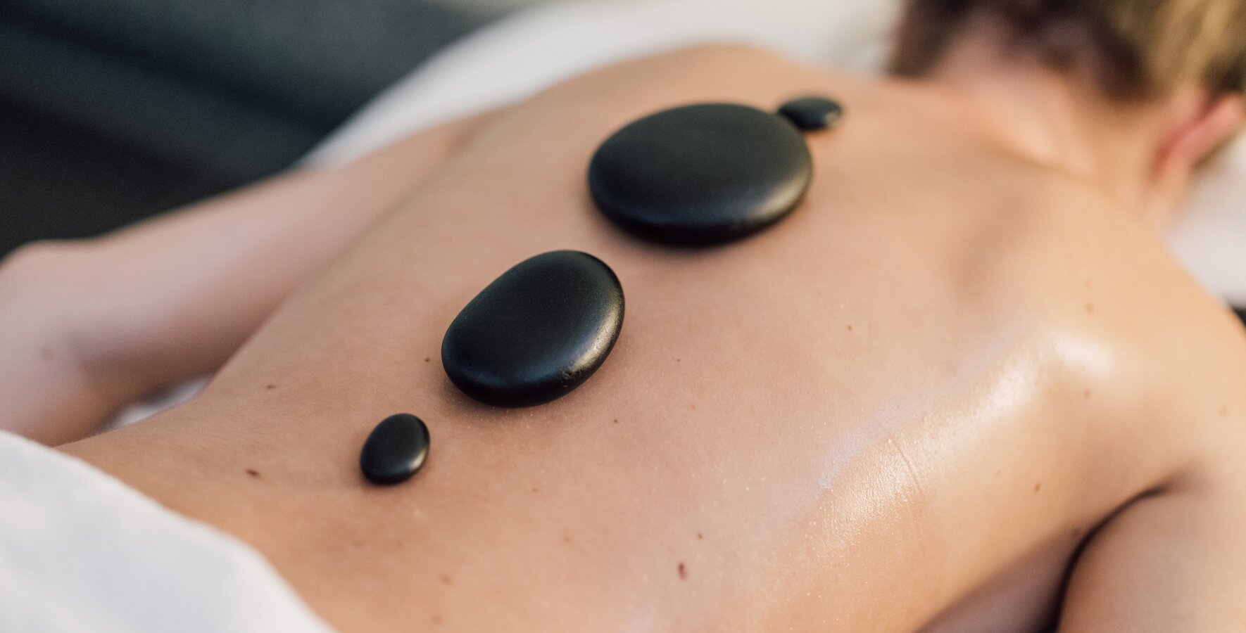 Blonde Frau gönnt sich eine Hot Stone Massage im Vitality Spa des Spa Resort Geinberg | © Spa Resort Geinberg / Chris Perkles