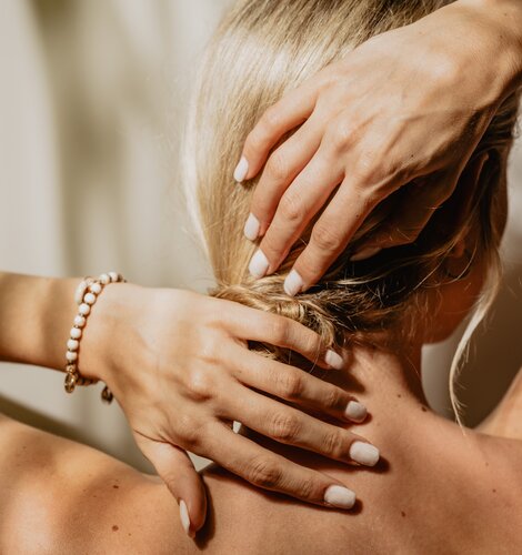 Blonde Dame streicht sich die Haare aus dem Nacken und fühlt sich vollkommen wohl im Vitality Spa | © Spa Resort Geinberg / Chris Perkles